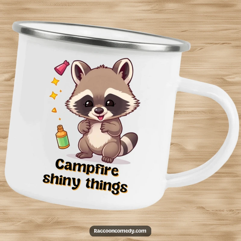 Funny enamel camping mug showcasing a mischievous raccoon gleefully juggling shiny objects, perfect for outdoor use.