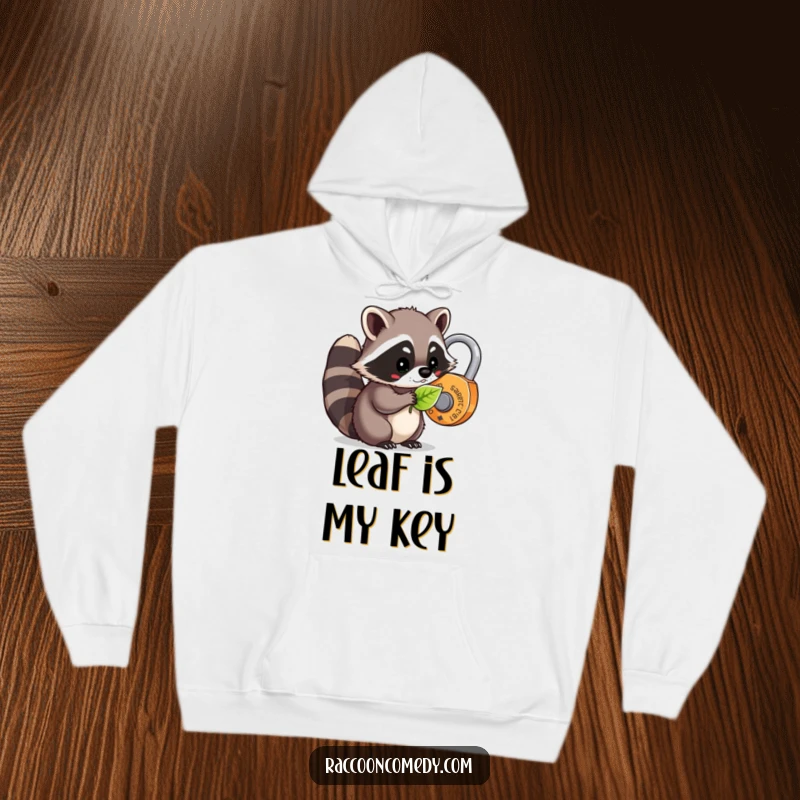 Funny kawaii raccoon using a leaf to unlock a whimsical lock, featured on a warm and humorous hoodie.