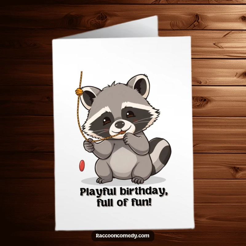 Funny Free Printable Birthday Card: Kawaii raccoon enthusiastically batting at a dangling string with pure joy and playful abandon.